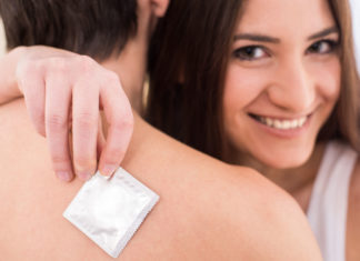 young couple in the arms woman is holding a condom