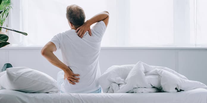 man sitting on a bed with back pain