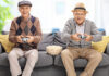 two older man playing kids game on the sofa