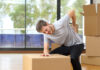 Man suffering back ache moving boxes