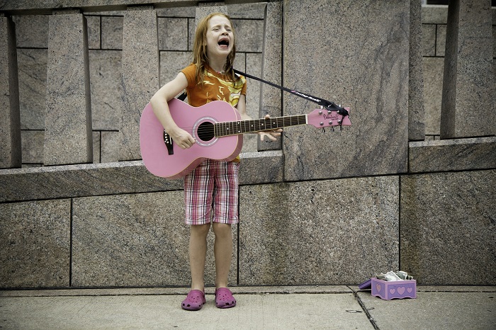 picture of a girl playing guitar in front a wall