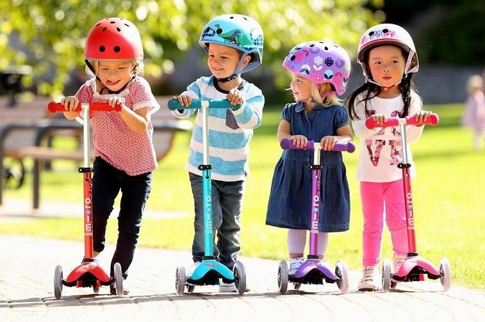 four little kids on scooters with nature background