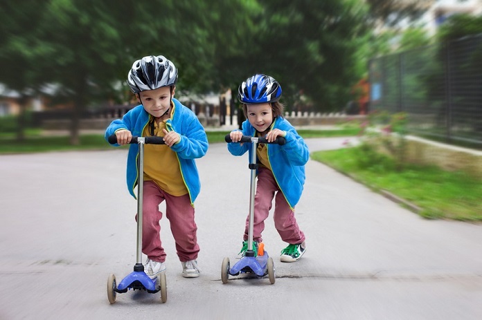 two little kids having fun with scooters