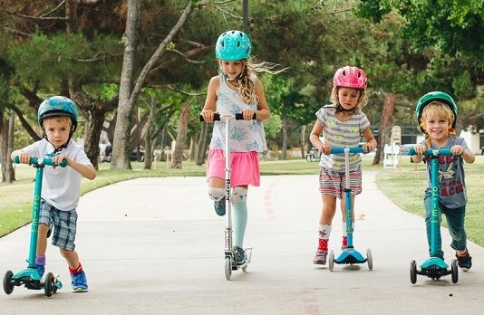 four kids on scooters in park
