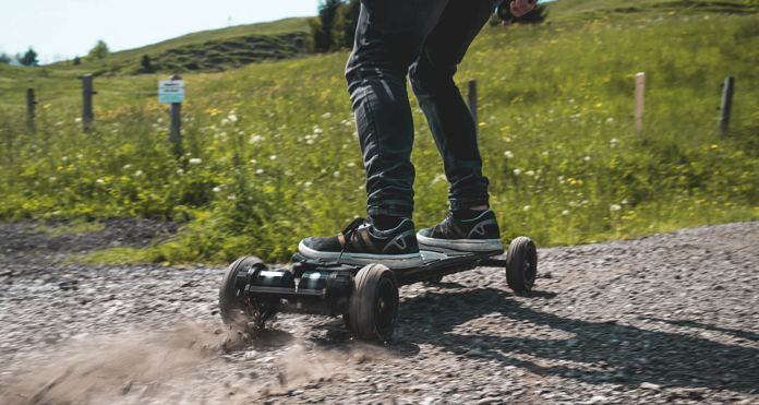 person riding onsra electric skateboard  on gravel road 