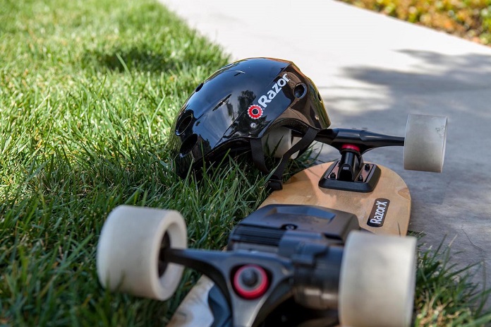 razor helmet and electric skateboard on grass