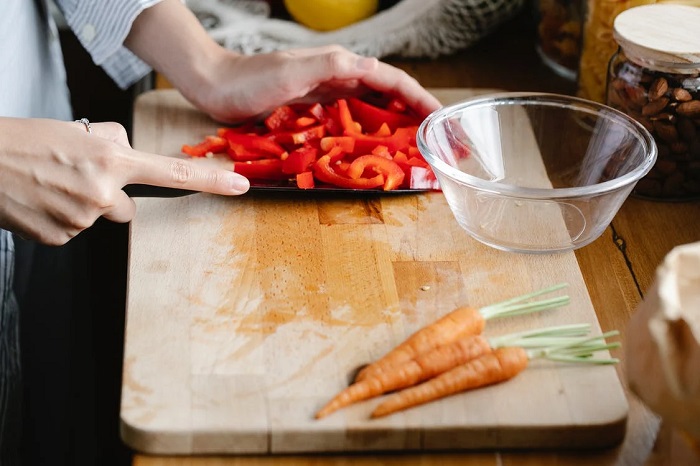 picture of a person chopping vegetables on a wooden chopping board 