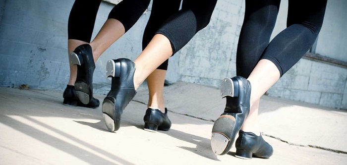 picture of three pairs of women legs in leggings and tap dance shoes on their feet on a concrete surface 