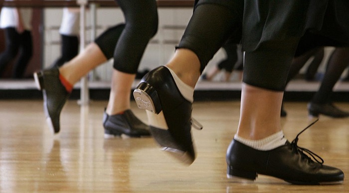picture of a persons feet dancing in tap dance shoes on wooden floor 