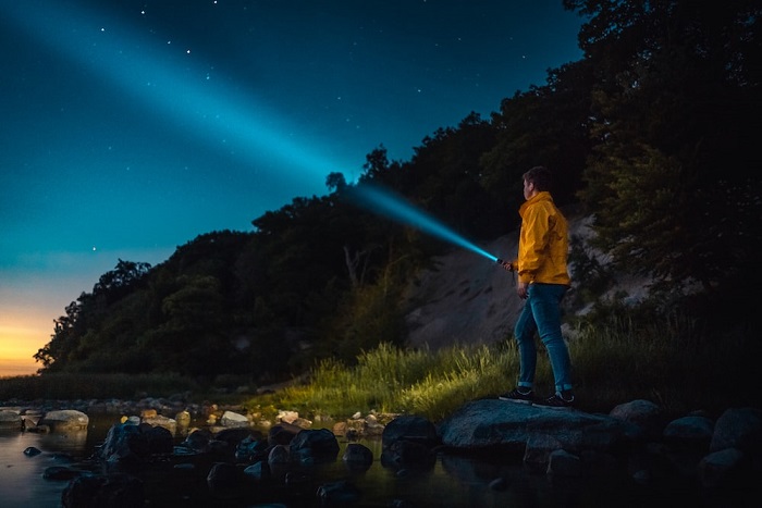 picture of a person on rocks in the wild holding a flashlight