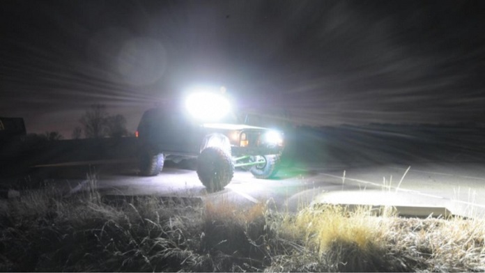 4x4 jeep with turned on led lights on a mountain at night