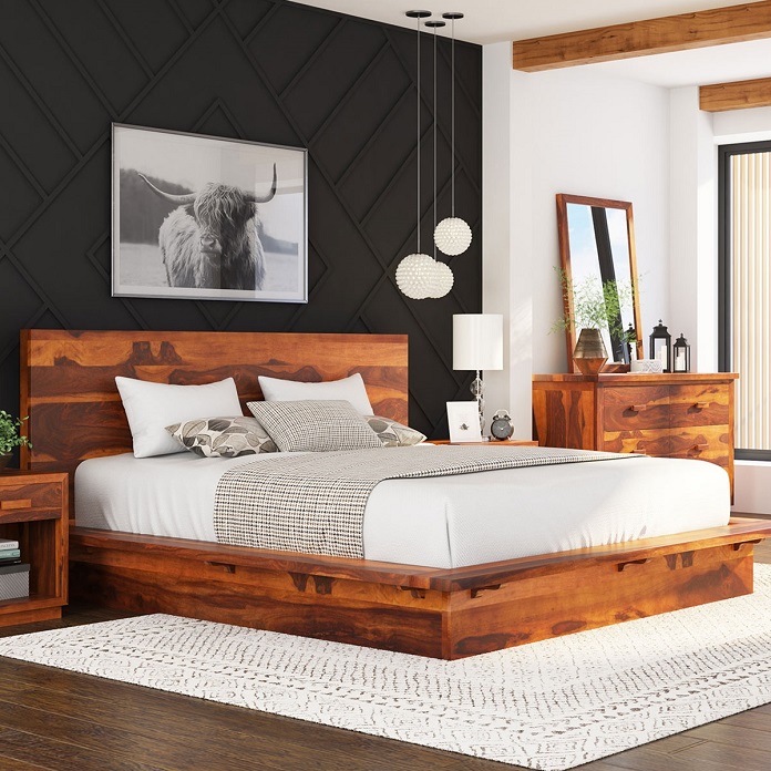 Wooden bed between 2 wooden bedroom bedside tables by the wall with picture