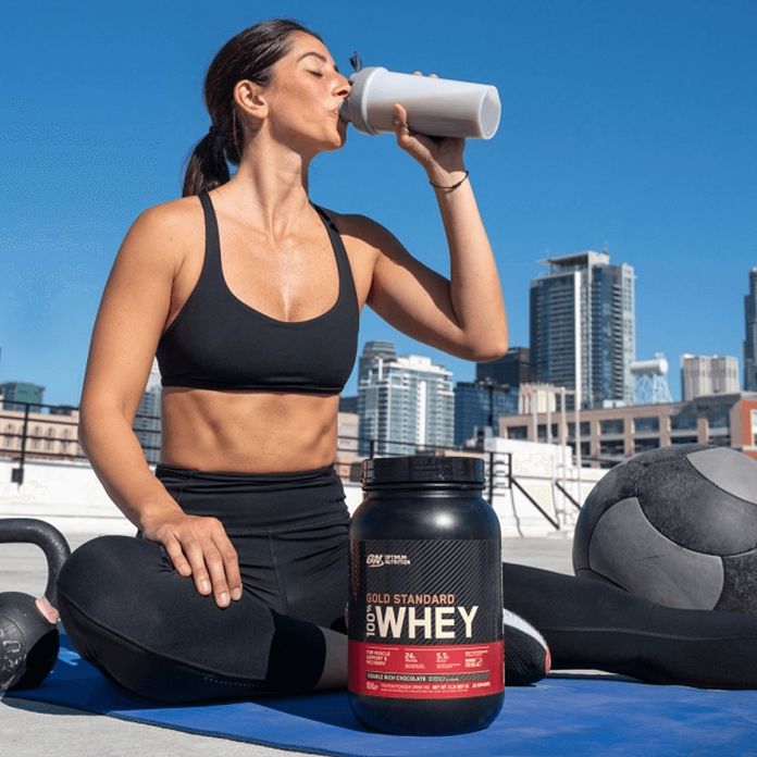 fit woman drinking gold standard whey protein shake